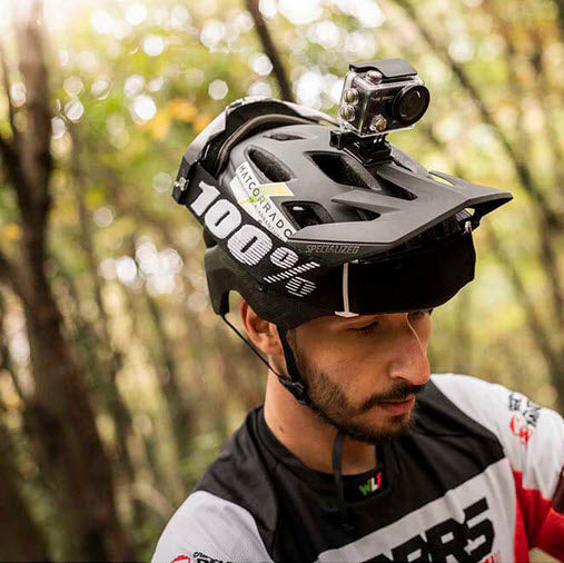 Kille med en cykelhjälm med en Midland actionkamera på huvudet i bakgrunden är det skog