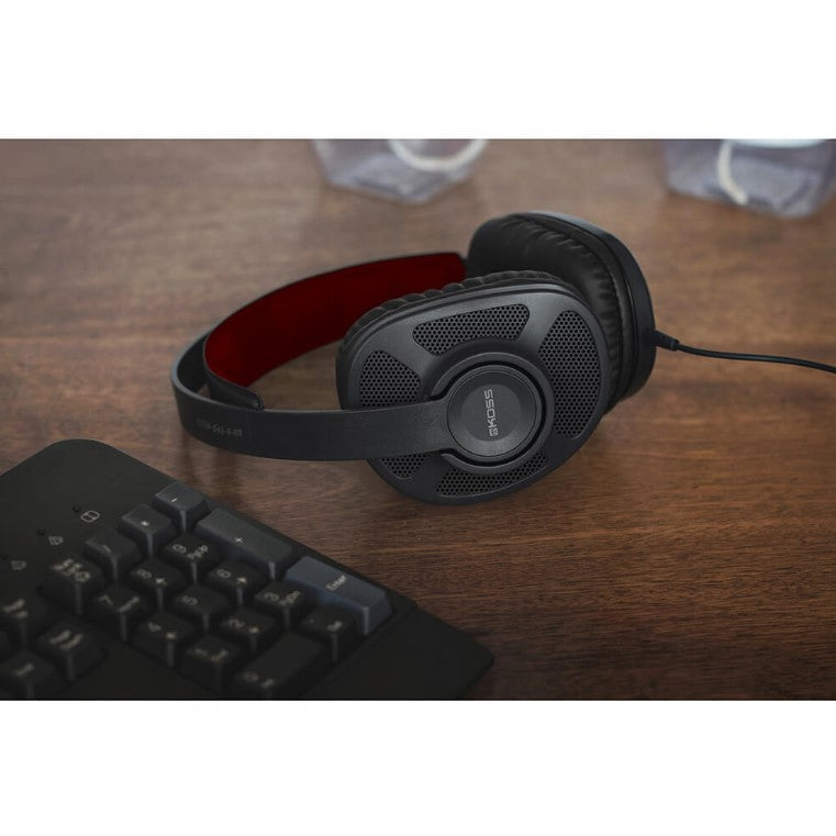 Koss gaming headset som ligger på ett träbord jämte ett svart tangentbord